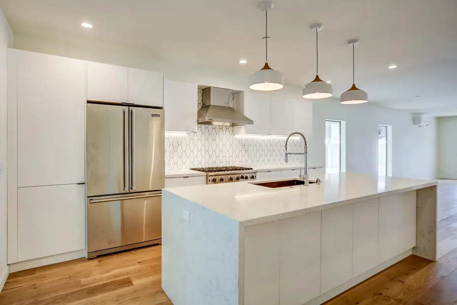 White kitchen with built-in refrigerator and waterfall island