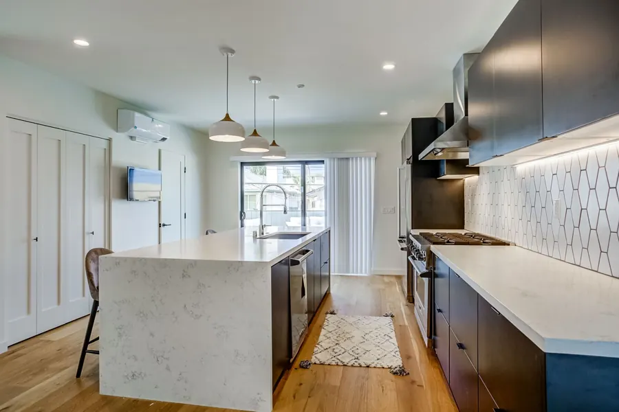 Dark-cabinet kitchen with waterfall island and patio door