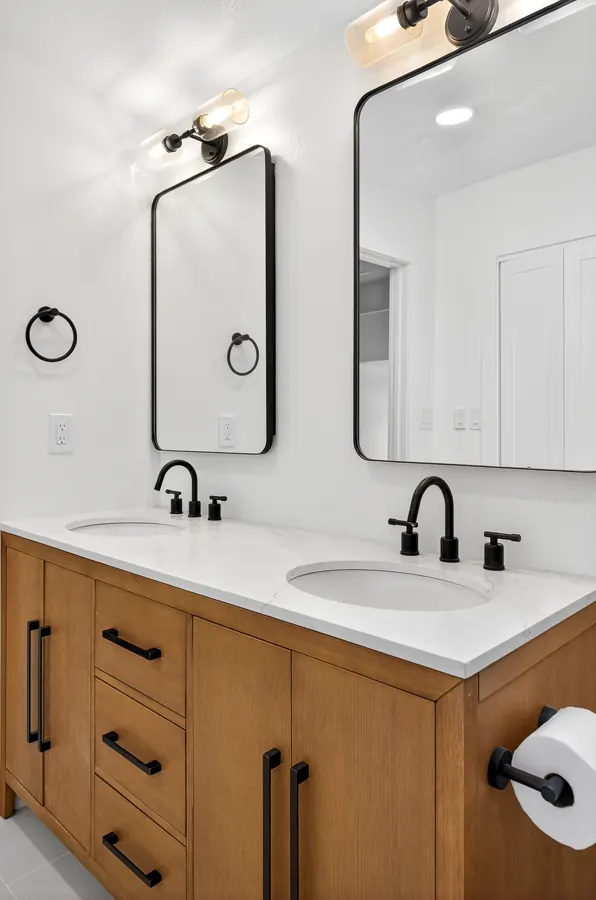 Double vanity with black-framed mirrors and sconces