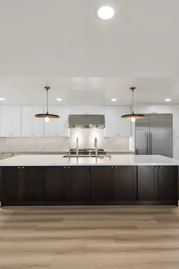 Del Cerro: Kitchen with dark island, white cabinets and quartz backsplash