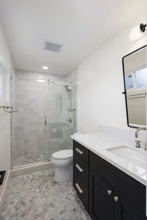 Bathroom with black vanity and tiled glass shower