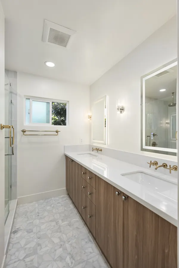 Bathroom with walnut double vanity and brass fixtures