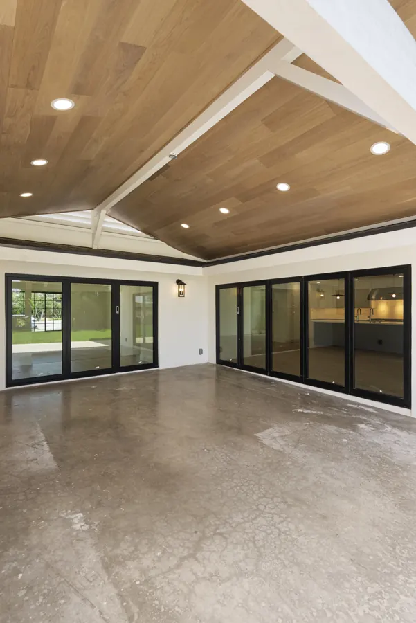 Covered patio with wood ceiling and black-framed glass doors