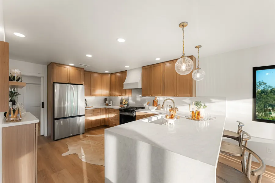Oak kitchen with waterfall quartz peninsula and bar stools