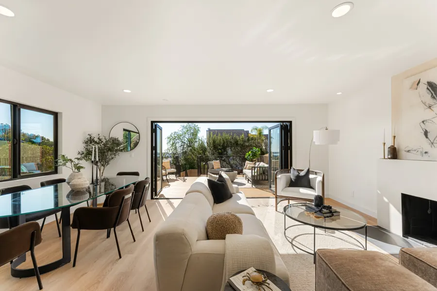 Living and dining room with folding glass doors open to the deck
