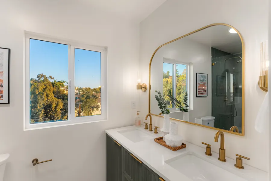 Bathroom with green fluted vanity and arched brass mirror