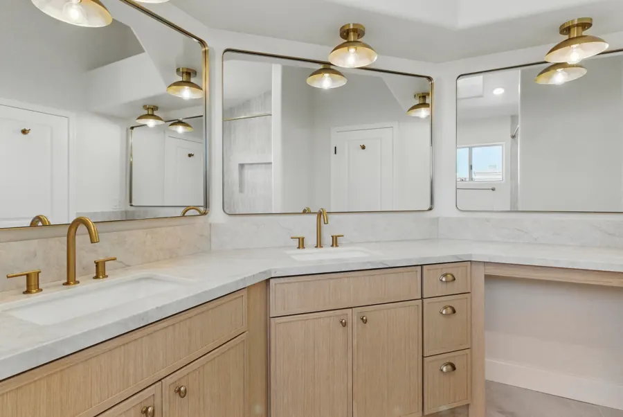 Corner double vanity with brass-framed mirrors