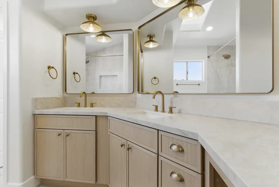 Corner double vanity with brass mirrors and fixtures