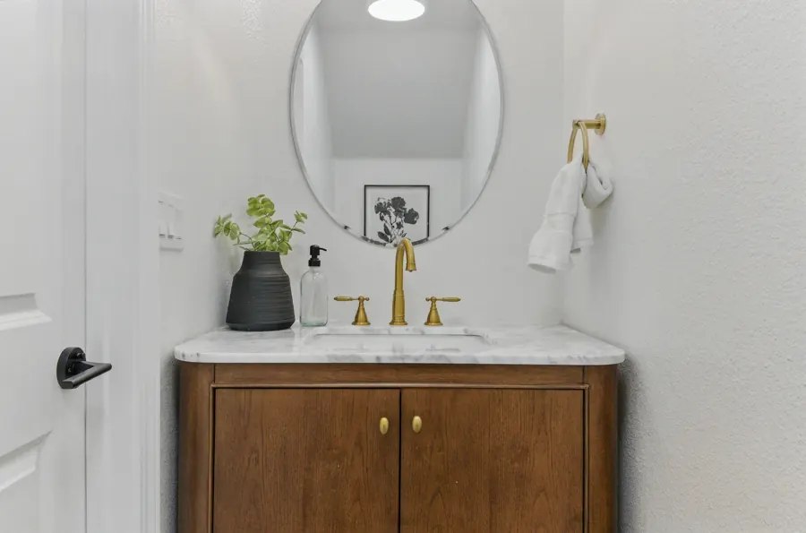 Powder room with walnut vanity and oval mirror