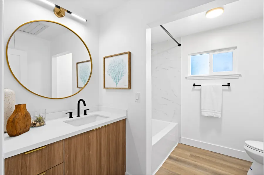 Bathroom with round mirror and walnut vanity