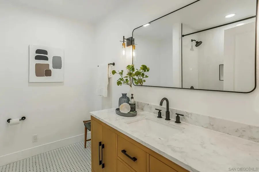 Bathroom with oak vanity, marble top and black fixtures